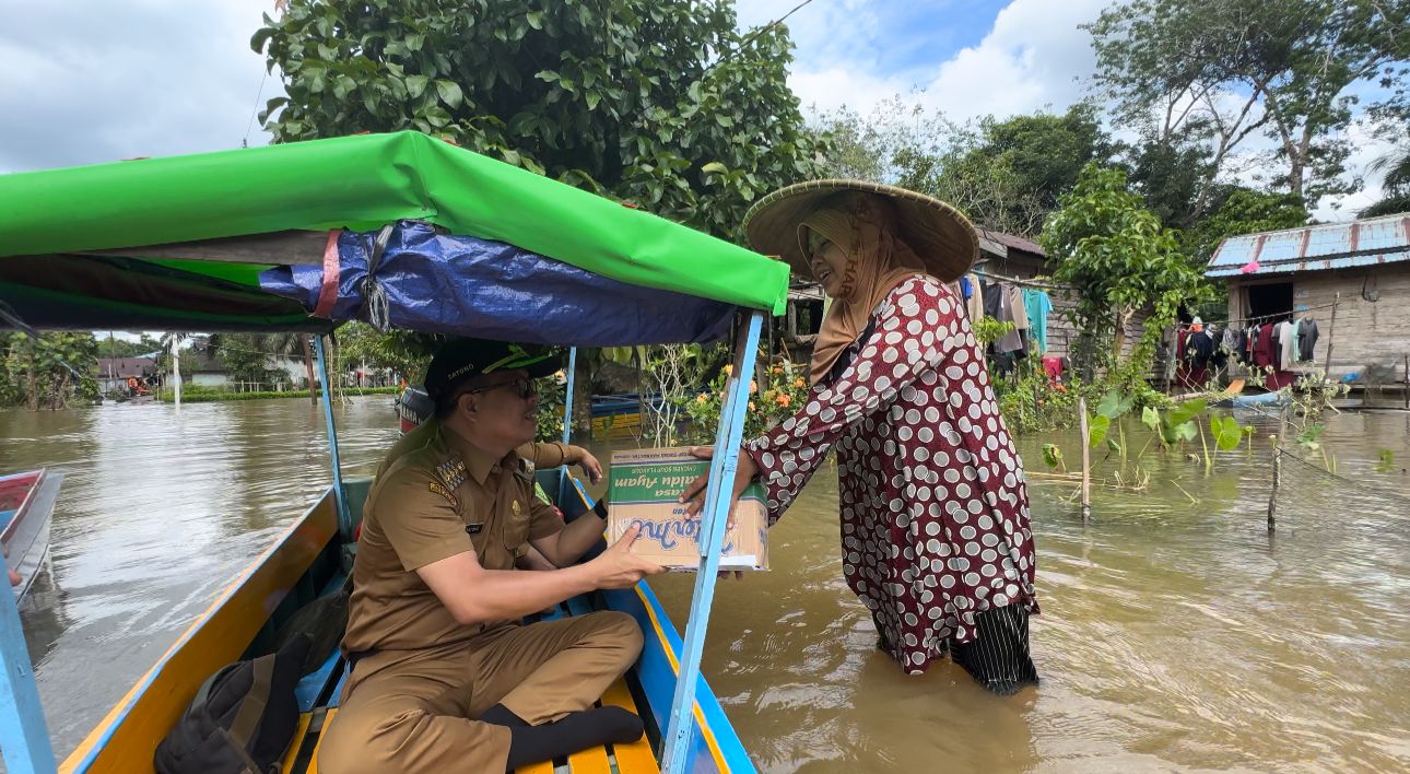 BERI BANTUAN: Bupati Sambas Satono terjun langsung ke daerah banjir di Dusun Sepandak, Desa Sepantai, Kecamatan Sejangkung oada Senin (2/12) untuk memberikan bantuan.