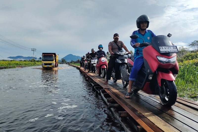 Pengendara sepeda motor melewati jembatan sementara yang dibangun atas inisiatif warga.