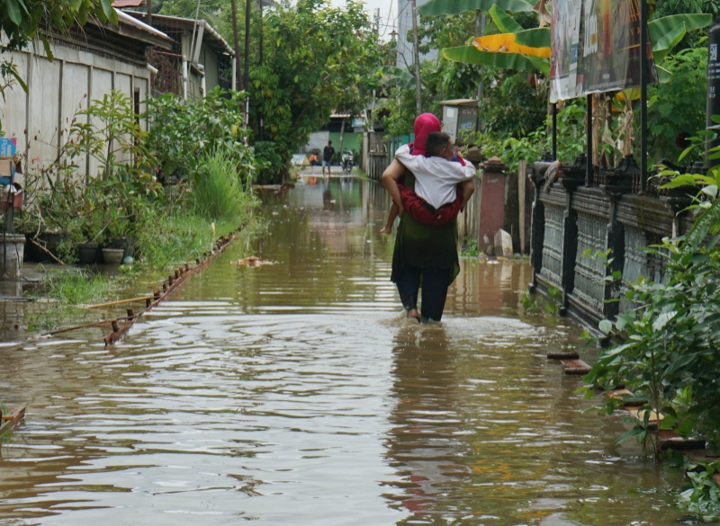 BANJIR ROB: Seorang ibu mengendong anaknya saat terjadi banjir rob di sekitar kawasan Parit Haji Muksin, Pontianak.