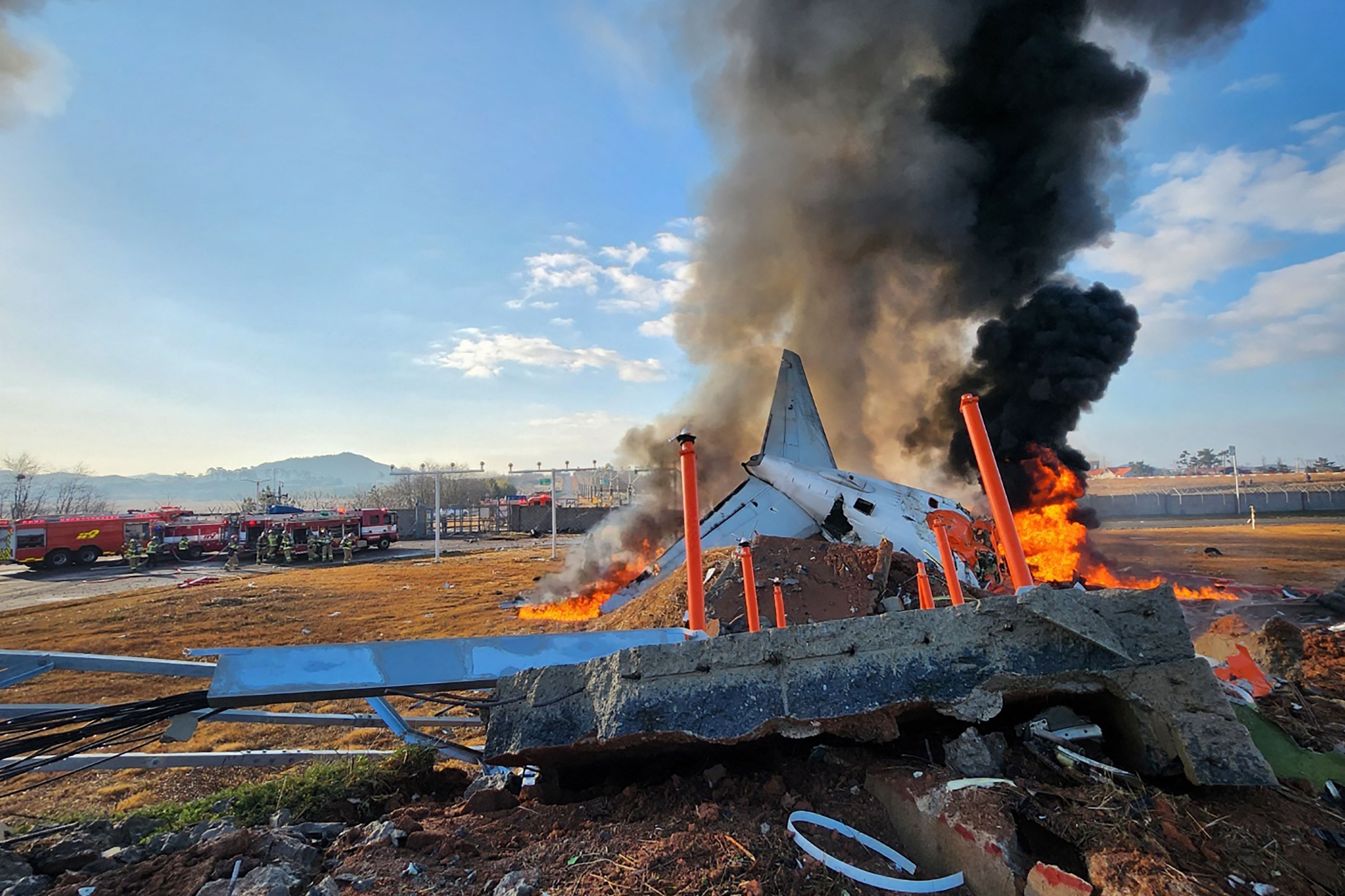 TERBAKAR: Api dan asap membubung dari bagian ekor pesawat seri Boeing 737-800 Jeju Air setelah pesawat itu jatuh dan meledak hingga terbakar di Bandara Internasional Muan di Provinsi Jeoll Selatan.