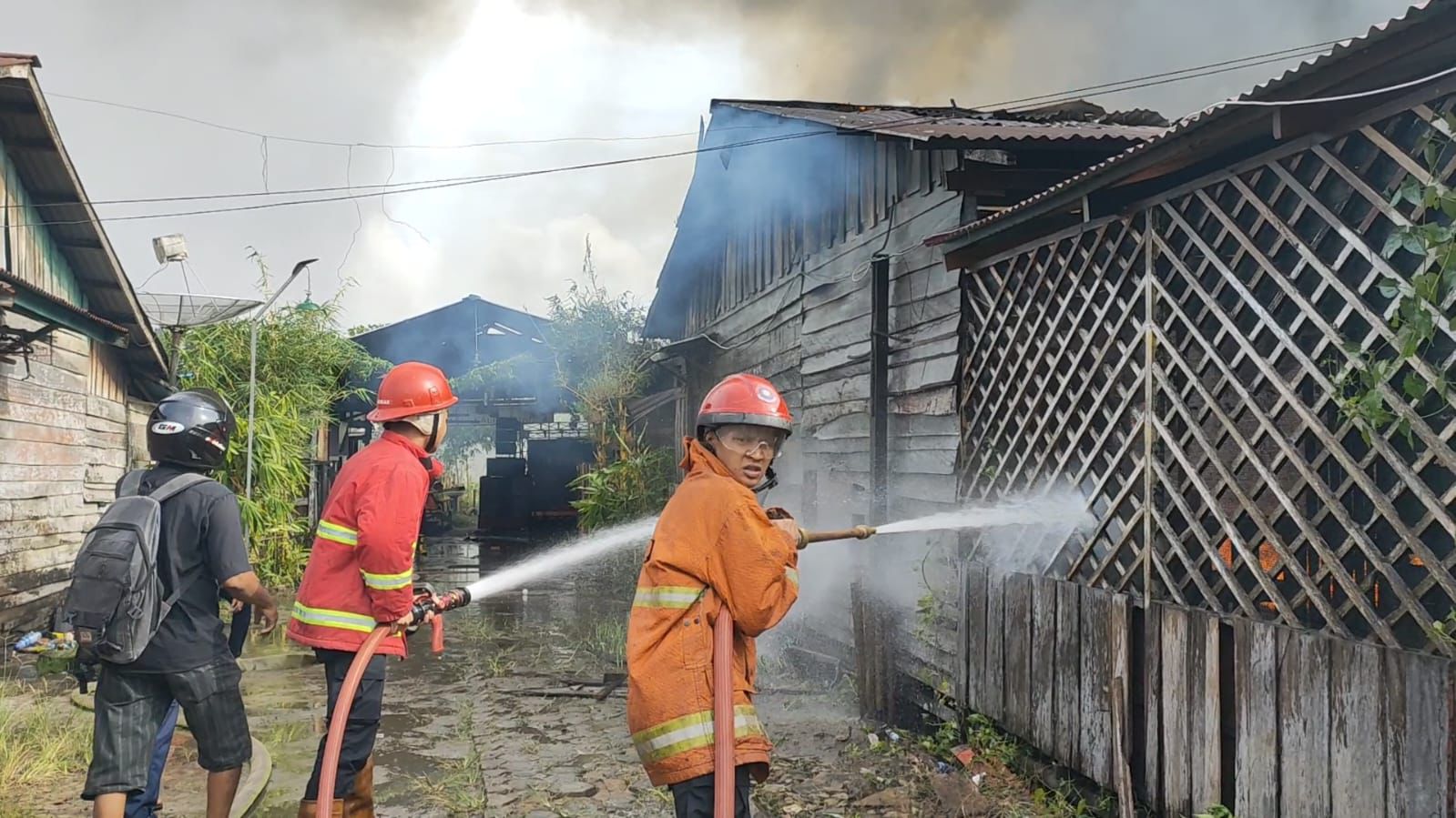 TERBAKAR: Petugas berupaya memadamkan api yang melahap kios di Jalan M.T Haryono, Minggu (5/1) sore.