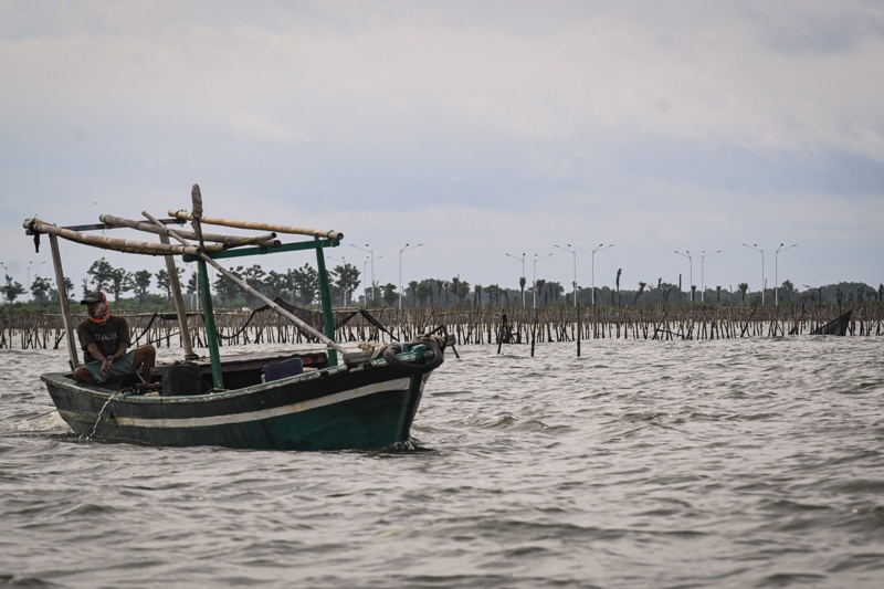 Perahu nelayan melintas di dekat pagar laut misterius di kawasan pesisir Kabupaten Tangerang, Banten, Kamis (9/1).