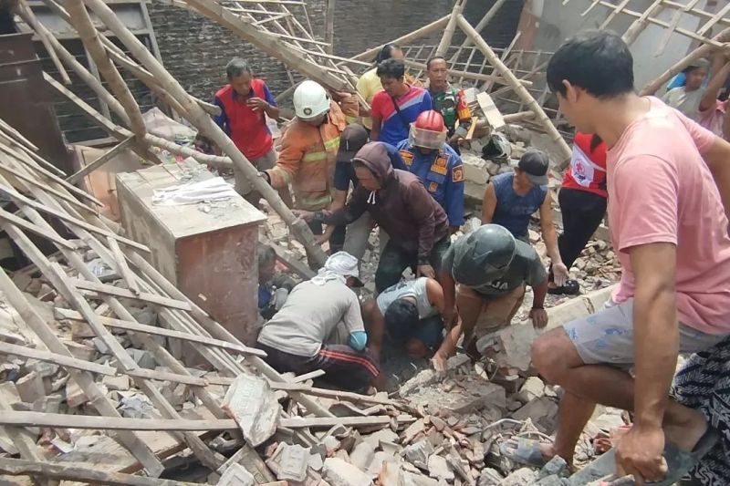 DIEVAKUASI: Korban dievakuasi warga dan petugas dari puing reruntuhan rumah yang ambruk akibat ledakan, Senin (13/1).