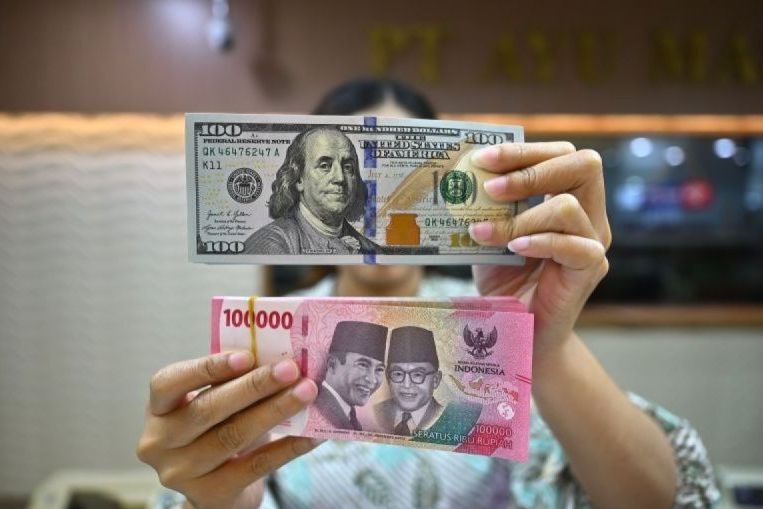 Arsip foto. Petugas menjunjukkan uang pecahan dolar AS dan rupiah di gerai penukaran mata uang asing di Jakarta, Jumat (2/1/2025).