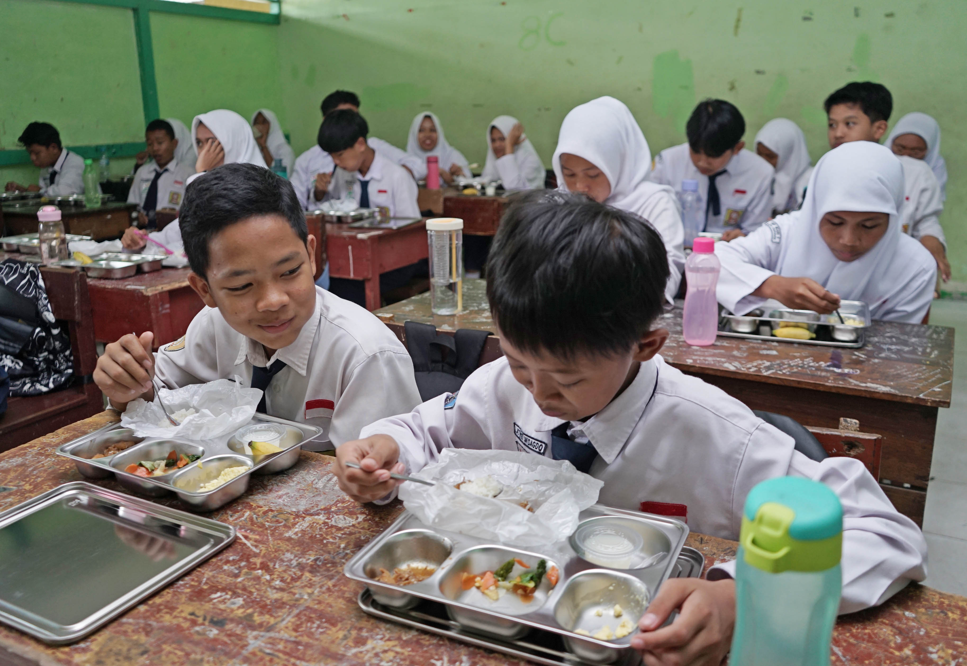 Pelajar SMP Negeri 9 Pontianak Jalan Pangeran Natakusuma menyantap menu makan bergizi gratis. Hari pertama pelaksanaan makan bergizi