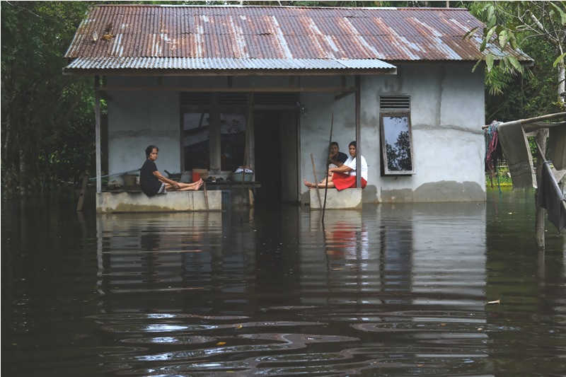 Tiga warga duduk di teras rumah yang terendam banjir di Desa Korek, Kecamatan Sungai Ambawang, Kabupaten Kubu Raya, Kalimantan Barat, Jumat (31/1).
