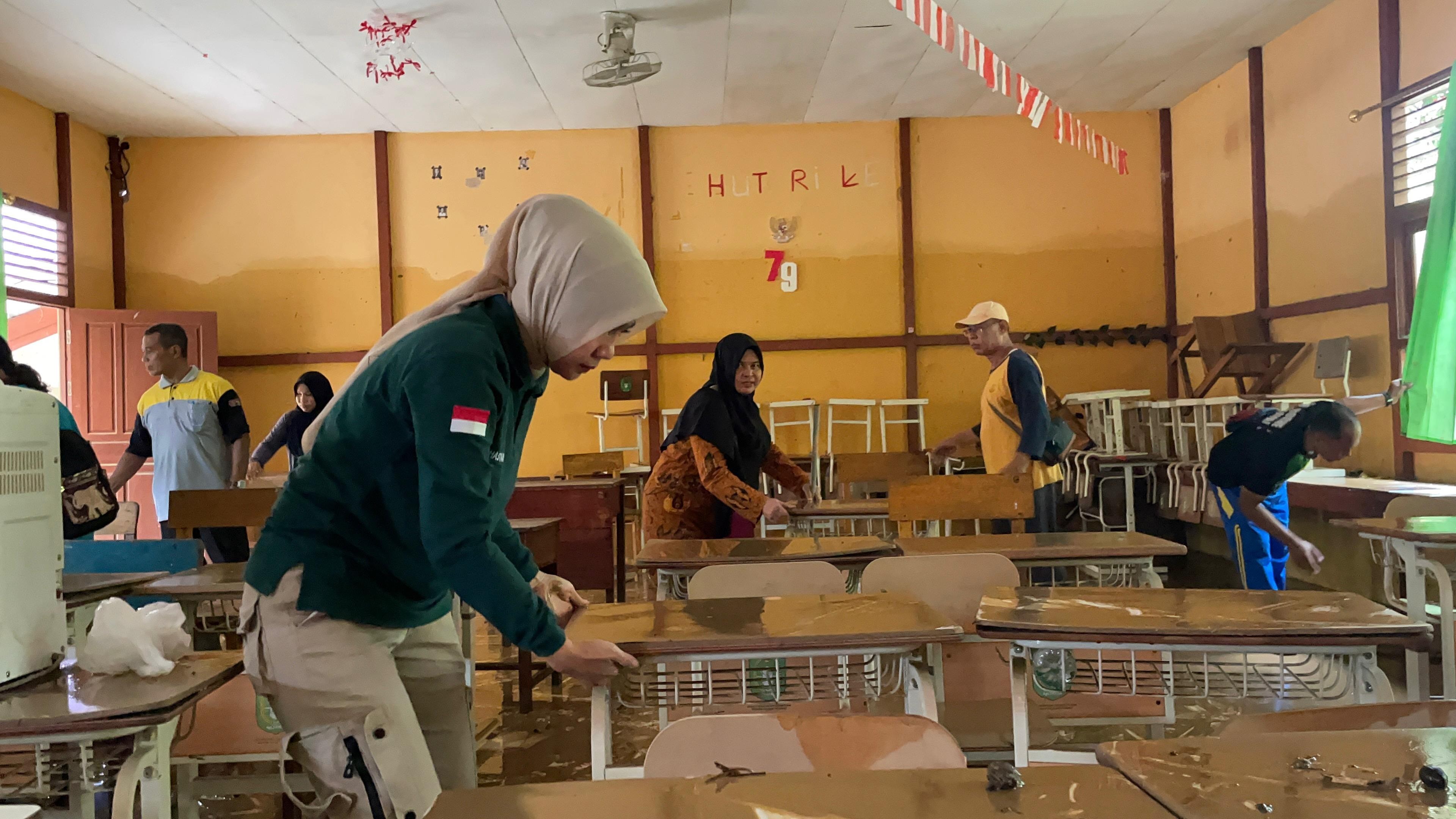 BERSIHKAN: Kepala Disdikbud Kalbar Rita Hastarita turut membersihkan sekolah yang terdampak banjir di Kabupaten Sanggau, baru-baru ini.