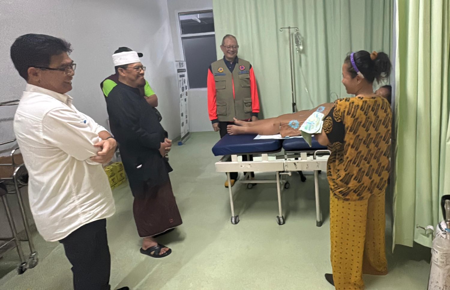 MENJENGUK: Pj Bupati Ismail bersama pejabat BNPB menjenguk korban banjir yang melahirkan di atas truk.