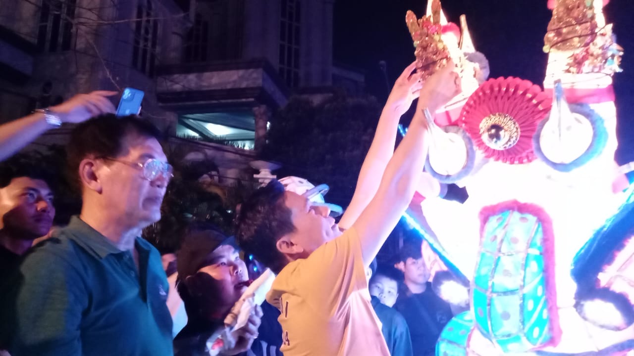 Yandi, Ketua Vois Dragon Sport memasangkan bunga emas pada acara naga buka mata, Minggu (9/2) malam.