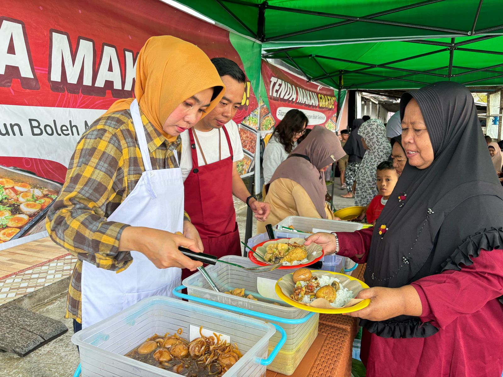 SAJIKAN: Rita menyajikan makan bergizi gratis kepada warga di Tenda Makan Gratis yang digelar di Gang Angket Dalam, Pontianak Timur, Selasa (18/2).