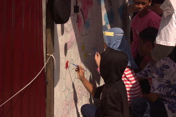 Anak-anak tampak antusias memainkan kuas di atas tembok yang telah memiliki sketsa gambar tertentu. Warna-warni cat kian mempercantik tembok di Gang Belibis, Minggu (23/2).