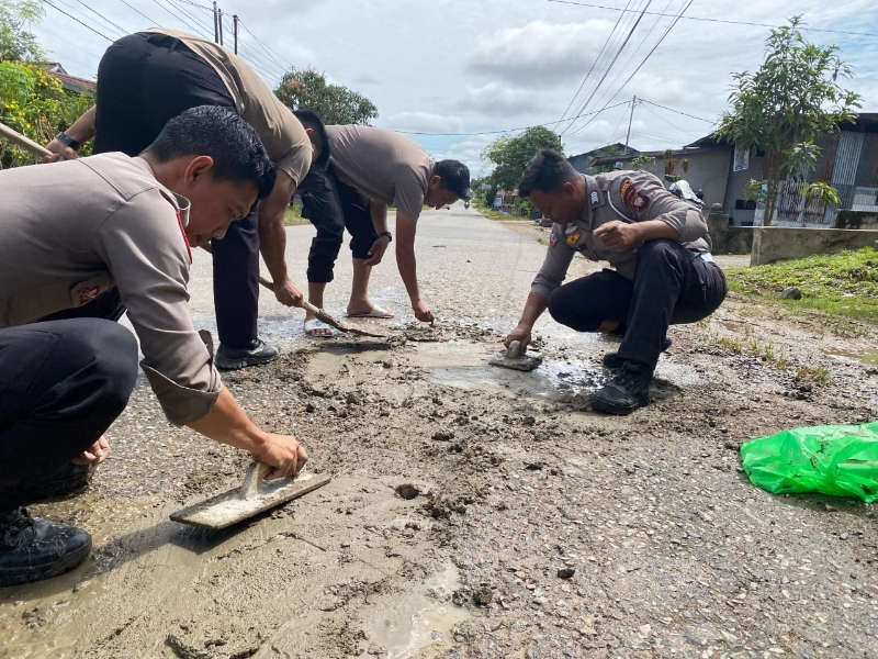 Personel Polres Sekadau menambal Jalan Merdeka Timur Sekadau pada Sabtu (08/03/2025).