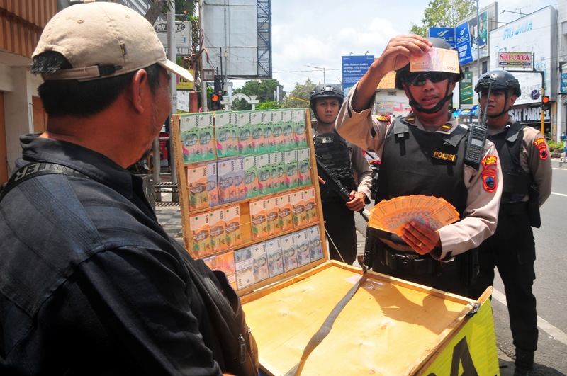 Anggota polisi Tim Unit Reaksi Cepat (URC) Muria Samapta Polres Kudus memeriksa uang di tempat jasa penukaran uang di Jalan Sunan Kudus, Kudus, Jawa Tengah, Jumat (21/3).