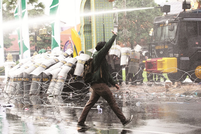 DEMO RICUH: Polisi menyemprotkan air dari water canon untuk menghalau sejumlah pengunjuk rasa yang beraksi untuk menyikapi UU TNI di Surabaya, Jawa Timur, Senin (24/3/2025).