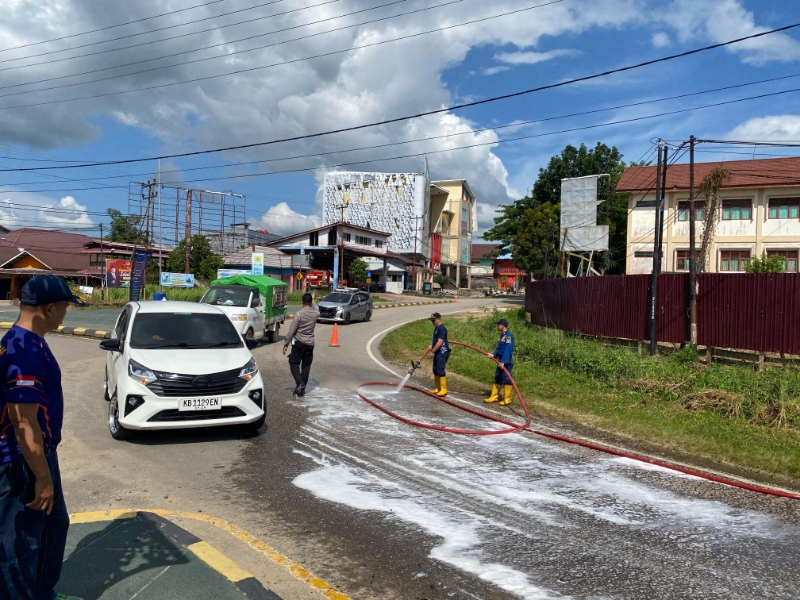 Petugas kepolisian dan damkar berjibaku membersihkan tumpahan solar yang sempat mengganggu akses transportasi di Kota Sekadau.