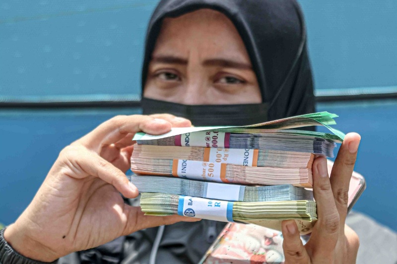 Seorang warga menukarkan uang di mobil Penukaran uang di komplek Masjid Al-Azhom, Kota Tangerang, Selasa (11/03). Nilai tukar rupiah terhadap dolar Amerika Serikat relatif melemah.
