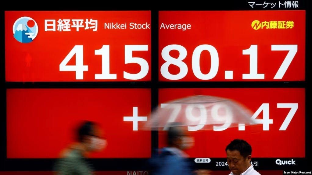 Foto arsip-Para pejalan kaki melintas di depan layar elektronik yang menampilkan rata-rata saham Nikkei Jepang di luar sebuah pialang di Tokyo.