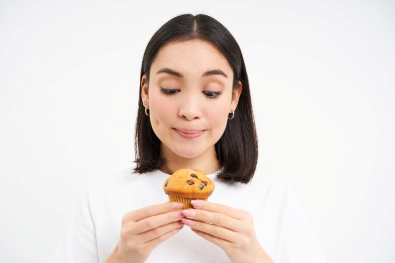 Seorang wanita memakan cupcakes, salah satu makanan yang dapat memicu tumbuhnya jerawat.