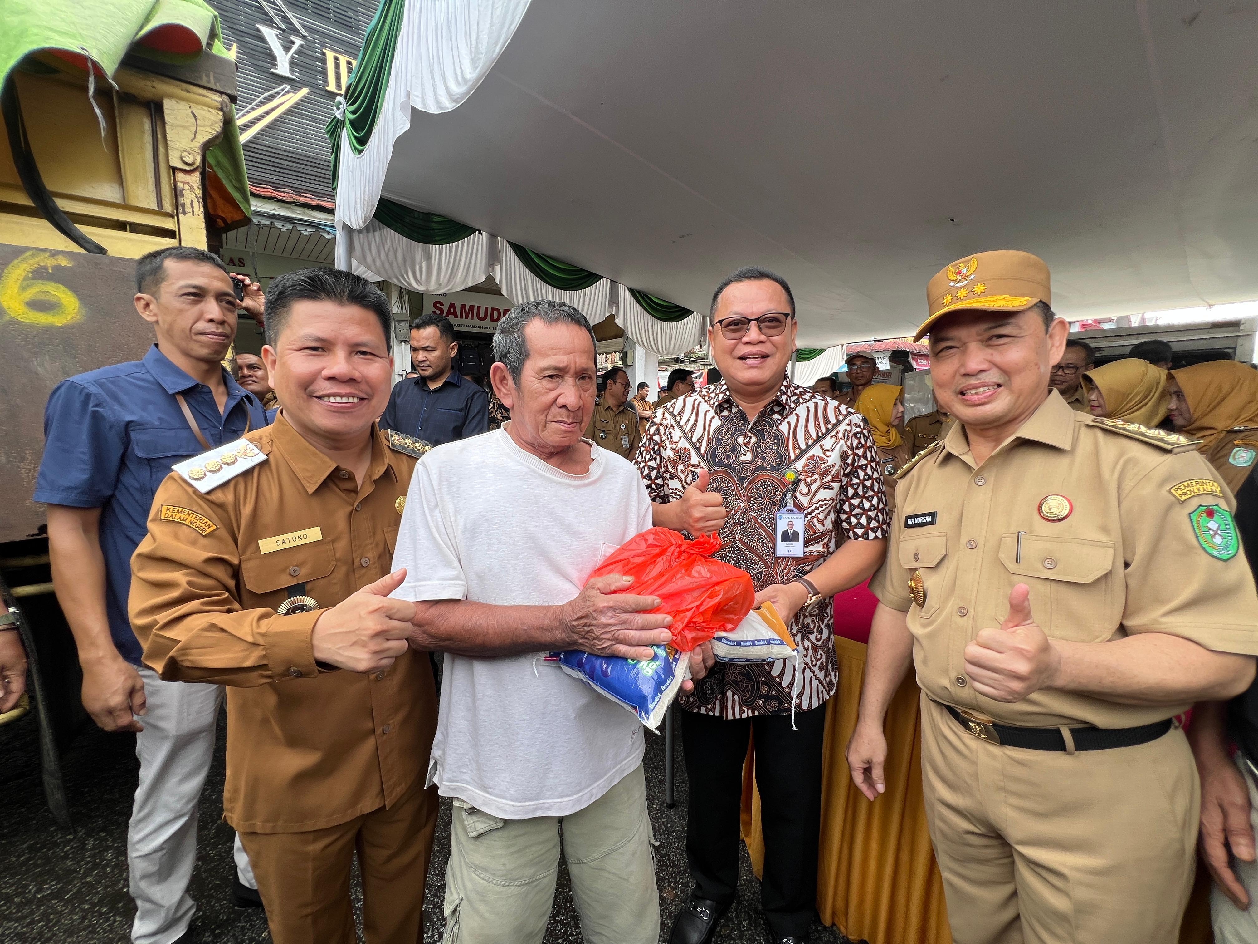 OPERASI PASAR : Gubernur Kalbar Ria Norsan (kanan), Dirut Bank Kalbar Rokidi dan Bupati Sambas Satono  (kiri) berfoto bersama warga yang hadir dalam operasi pasar di Pasar Rakyat Kabupaten Sambas.