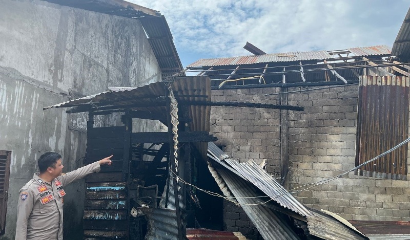 Petugas menunjukkan puing-puing sisa kebakaran rumah warga.