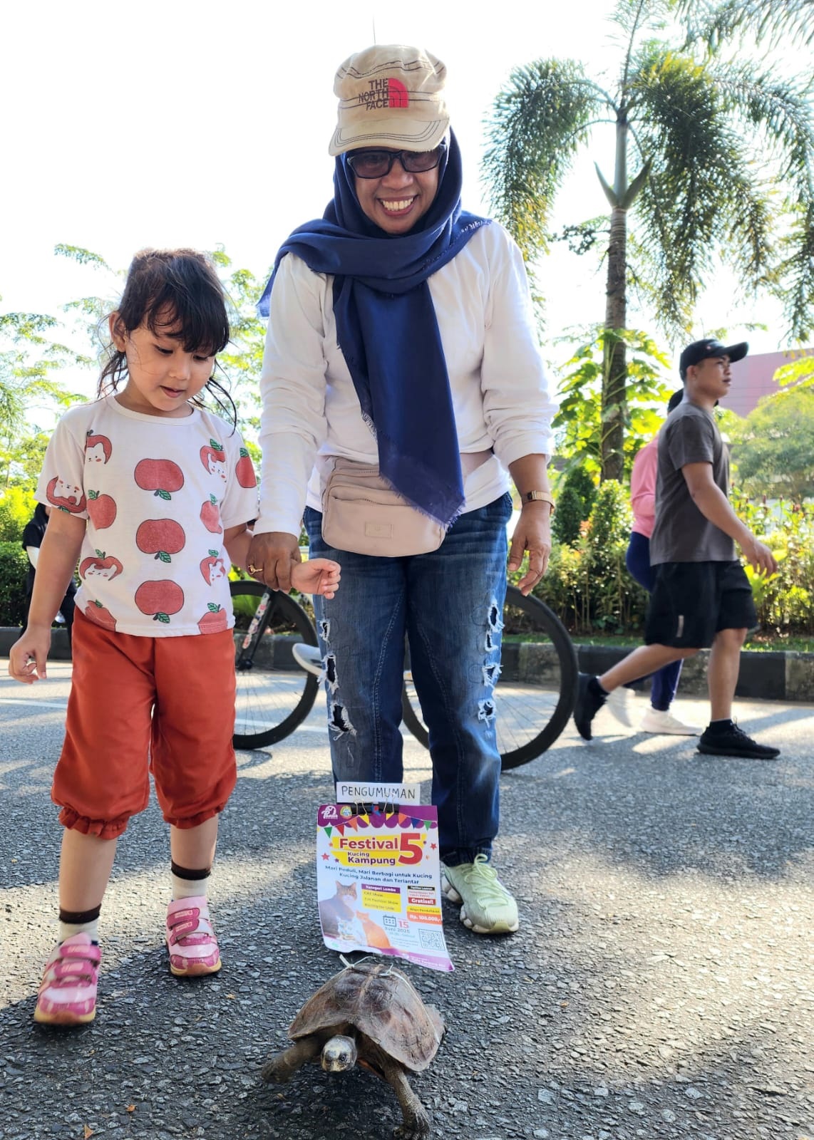 BAWA PENGUMUMAN: Ketua Panitia FKK 5, Emi Puterina, bersama kura-kura jantan bernama Torro saat sosialisasi FKK di area Car Free Day Jalan A. Yani, Pontianak, Minggu (25/5).