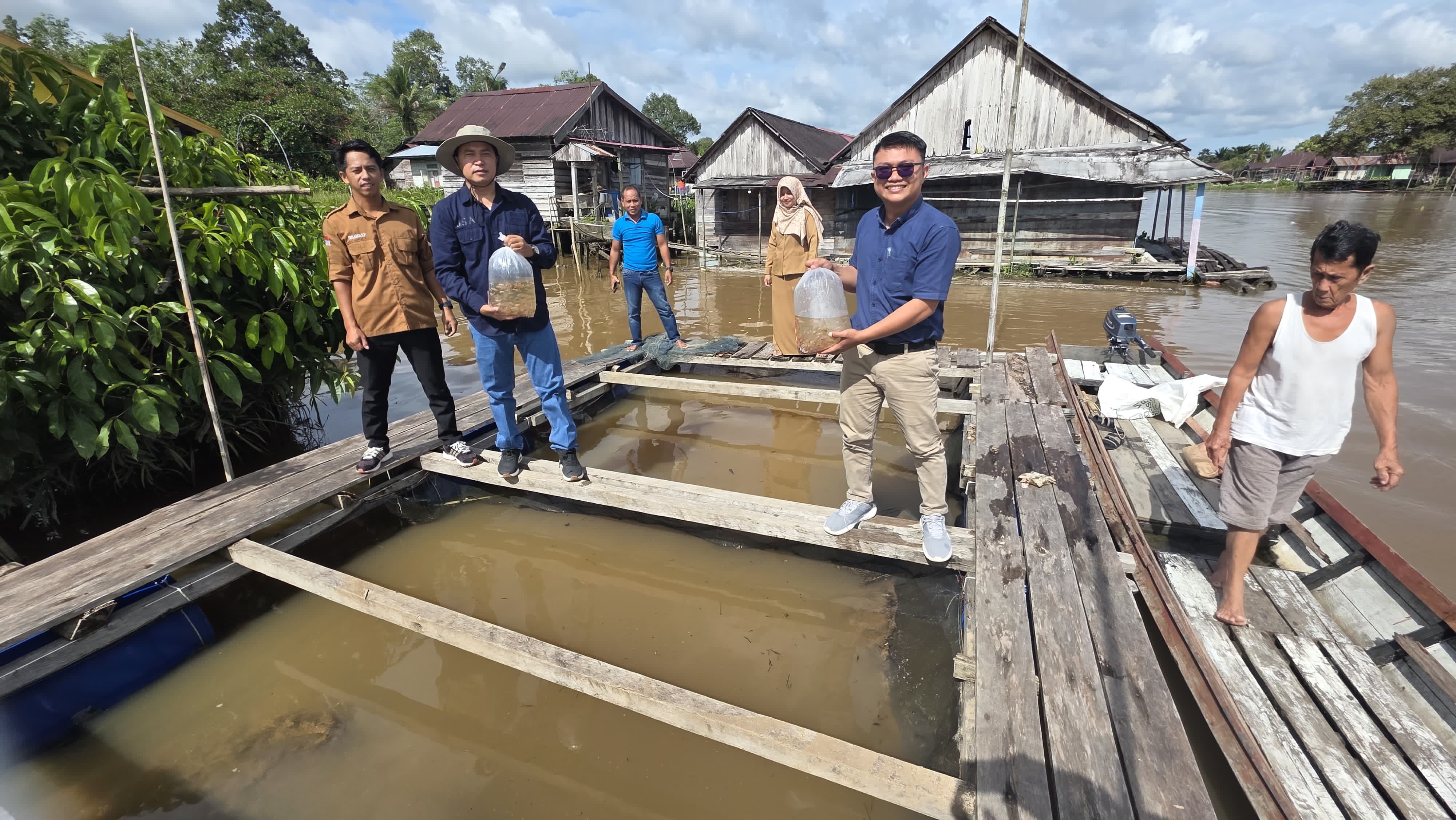 Masyarakat pembudidaya ikan taburkan bibit ikan dikolam setelah menerima penyerahan bantuan dari SEC