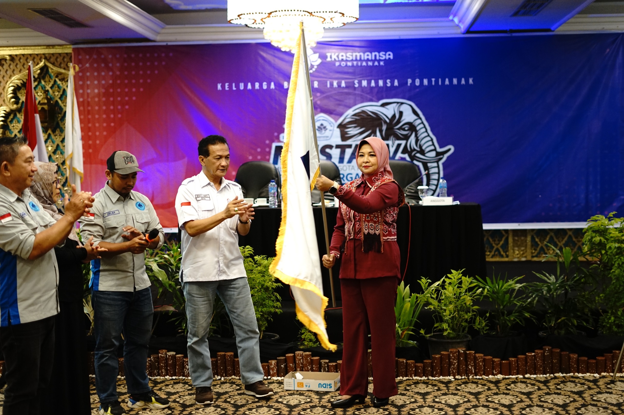 SMANSA: Windy Prihastari mengibarkan bendera pataka IKA SMANSA Pontianak usai dilantik sebagai Ketua periode 2025&ndash;2028.