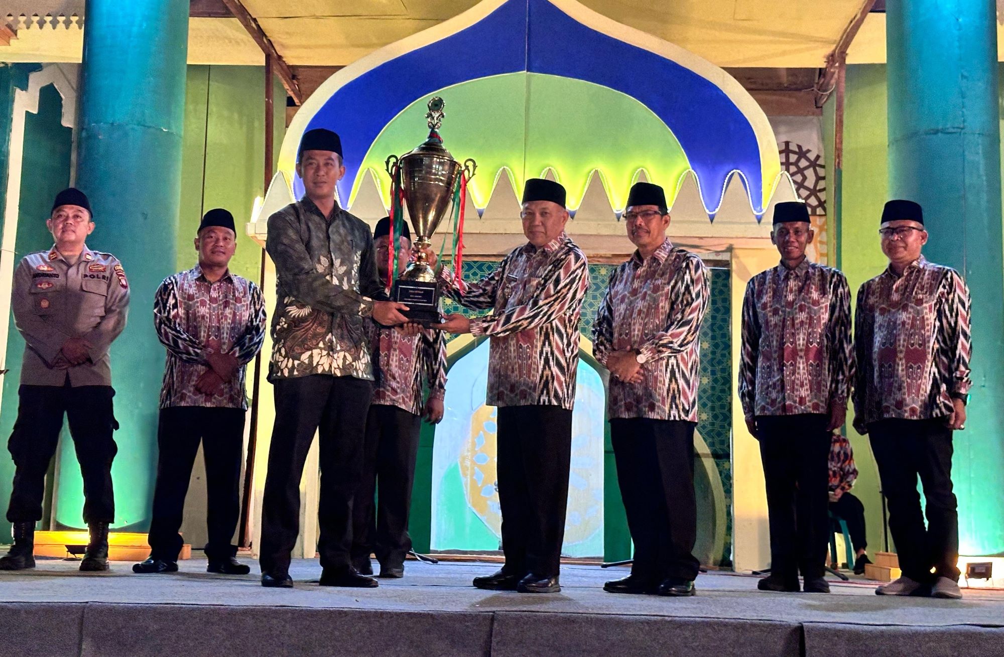 PIALA: Wabup Juli menyerahkan piala bergilir MTQ kepada Camat Anjongan Feri Ramadhani.