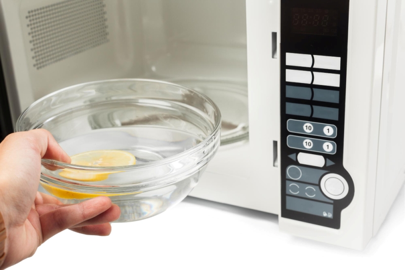 Ilustrasi membersihkan microwave dengan air dan lemon.