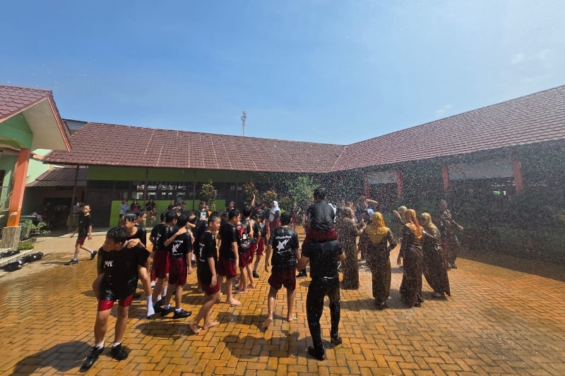 Siswa kelas VI beserta dewan guru SDN 02 Sungai Pinyuh merayakan kelulusan dengan bermandikan air semprotan dari pemadam Jaguar.