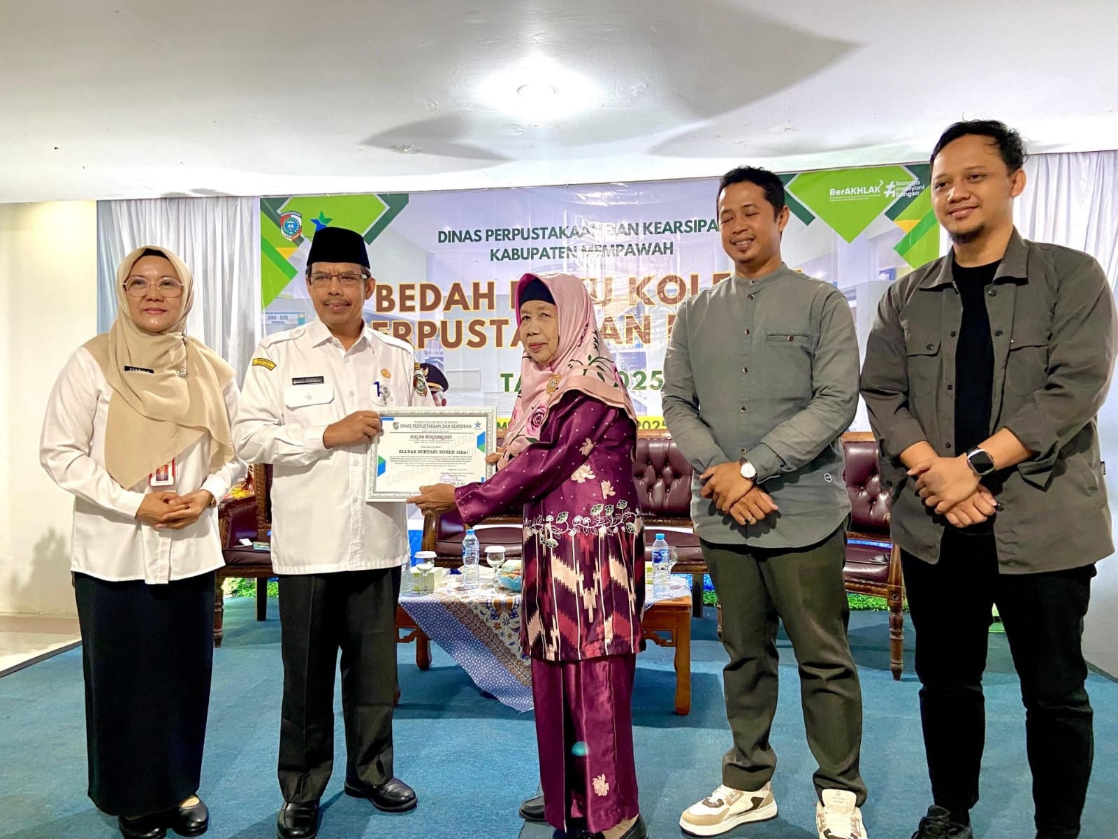 PENGHARHAAN: Sekda Ismail menyerahkan plakat penghargaan kepada istri dari almarhum Ellyas Suryani Soren.