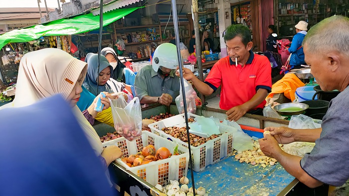 HARGA NAIK: Imam Sukoco pedagang bawang di Pasar Pagi Sungai Pinyuh sedang melayani pembeli.
