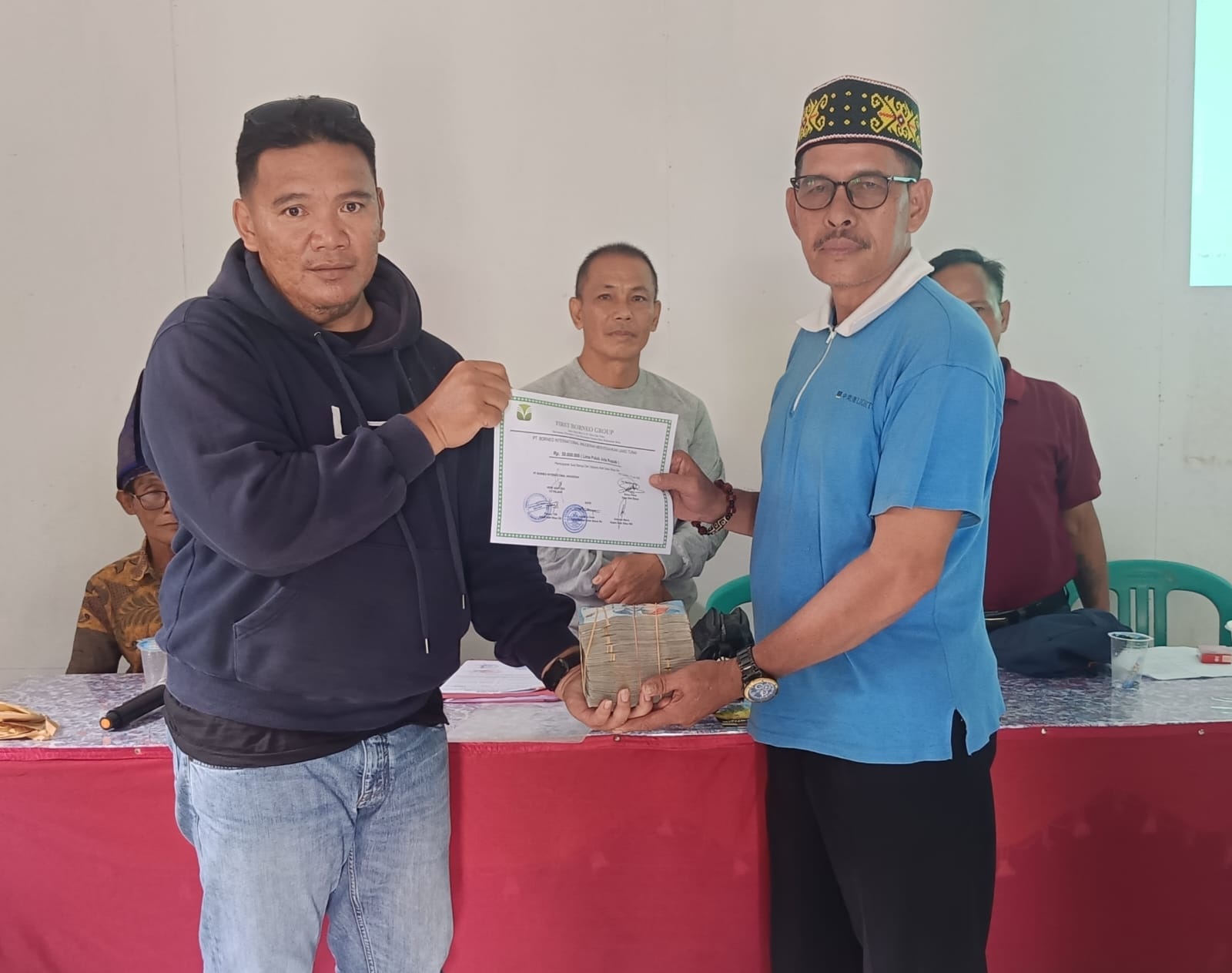 SANKSI : Penyerahan uang sanksi adat dari PT BIA kepada Ketua Tim Bela Benua Desa Sibau Hilir.