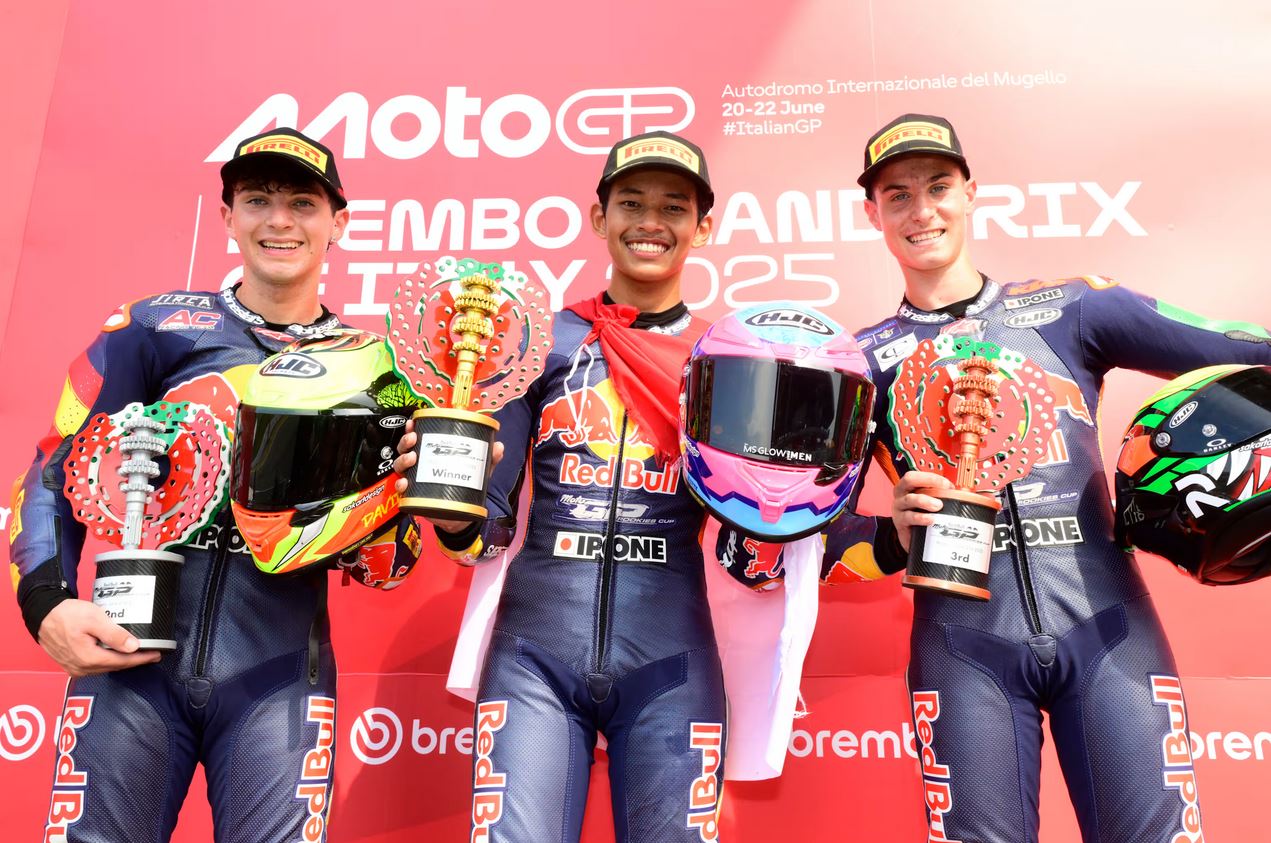 eda Ega Pratama (tengah) mengibarkan Merah Putih di podium tertinggi Red Bull MotoGP Rookies Cup 2025 di Sirkuit Mugello, Italia, Sabtu (21/6).