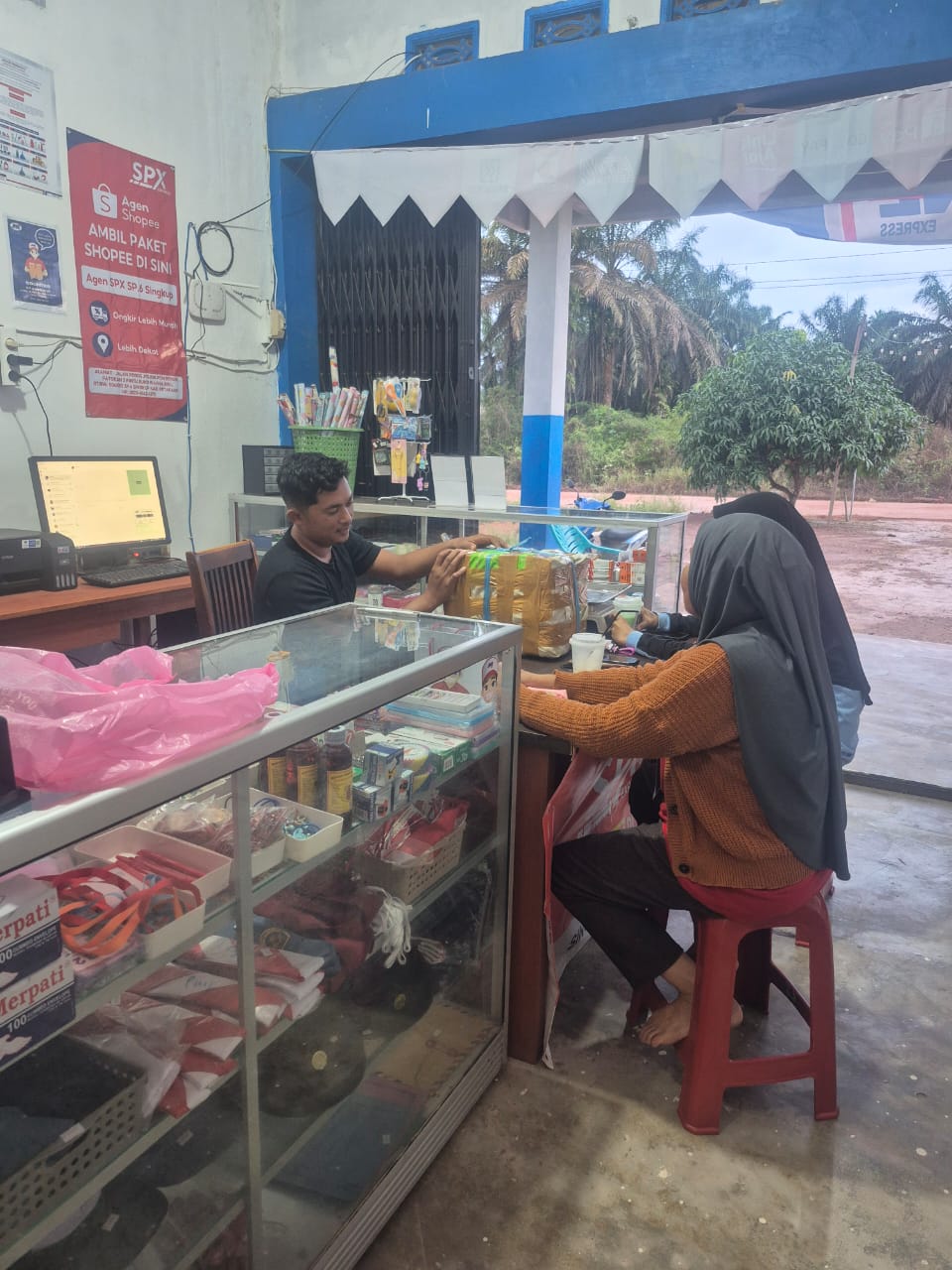 Proses pengiriman barang di agen JNE daerah perkebunan sawit.
