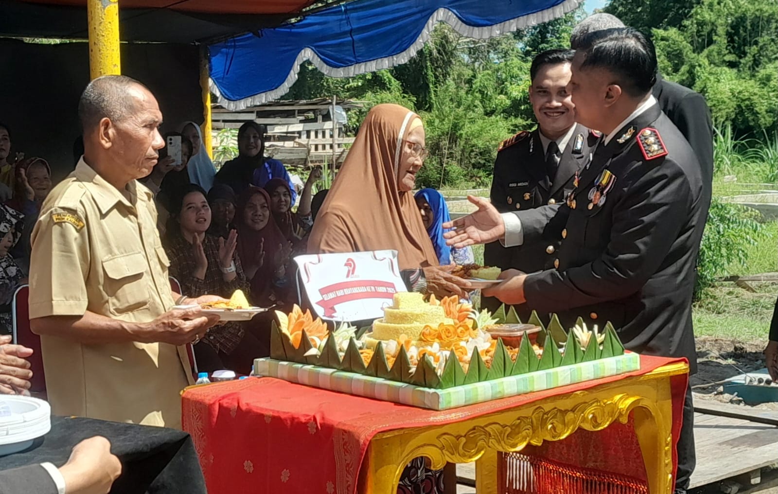 Kapolres Sambas serahkan potongan tumpeng ke warga saat syukuran HUT Bhayangkara.