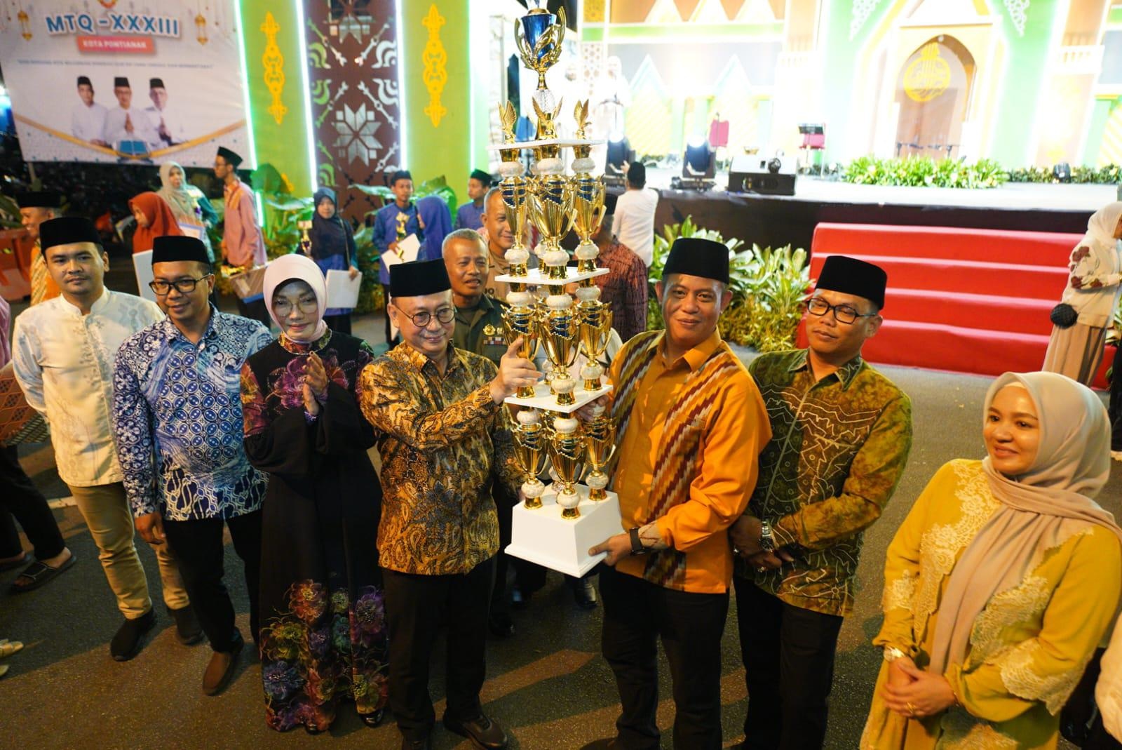 SERAHKAN PIALA: Wali Kota Pontianak Edi Rusdi Kamtono menyerahkan piala Juara Umum MTQ ke-33 Tingkat Kota Pontianak kepada Camat Pontianak Utara Indrawan.