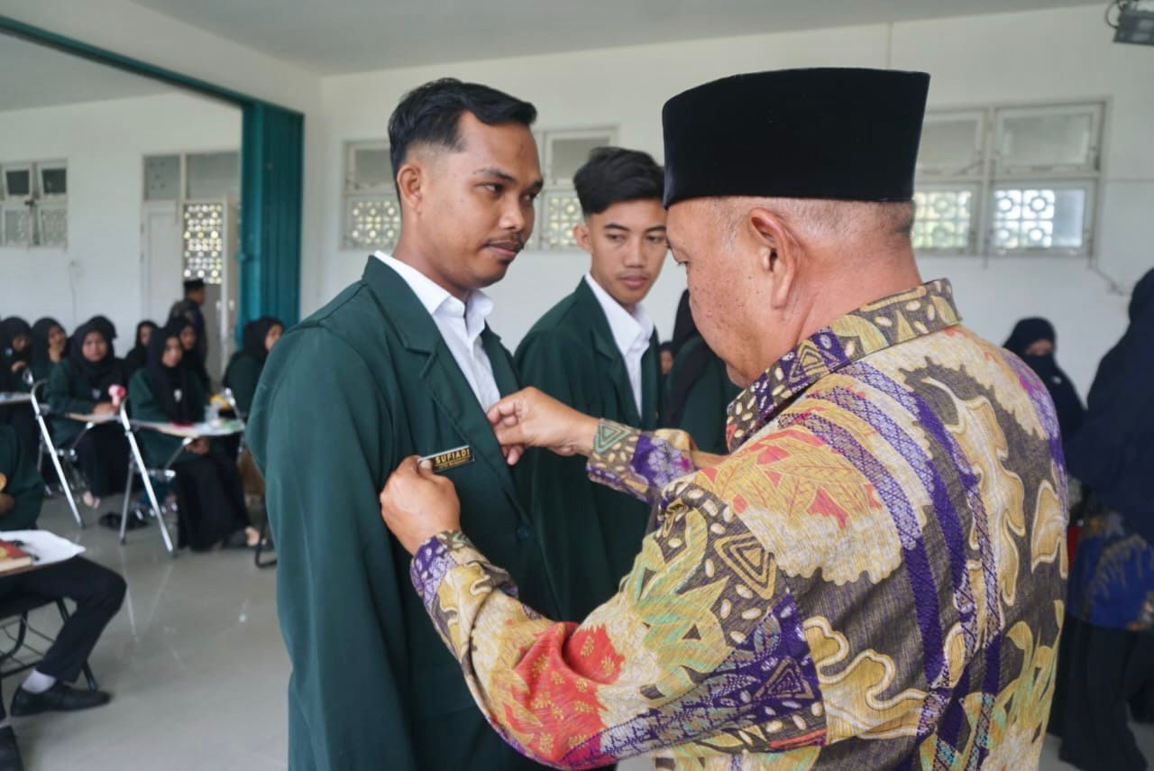 TANDA PESERTA: Wakil Bupati Mempawah Juli Suryadi, menyematkan tanda peserta pembekalan 77 mahasiswa STAIM yang akan melaksanakan praktik pengalaman lapangan.