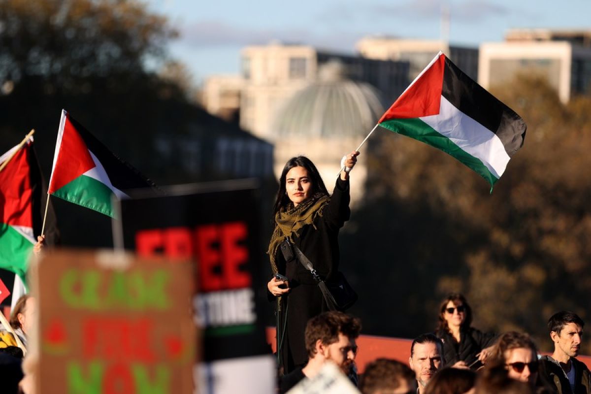 Seorang wanita di tengah kerumunan massa mengibarkan bendera Palestina. Ratusan ribu warga Inggris turun ke jalan dalam unjuk rasa di London Inggris itu pada Sabtu (11/11/2023).