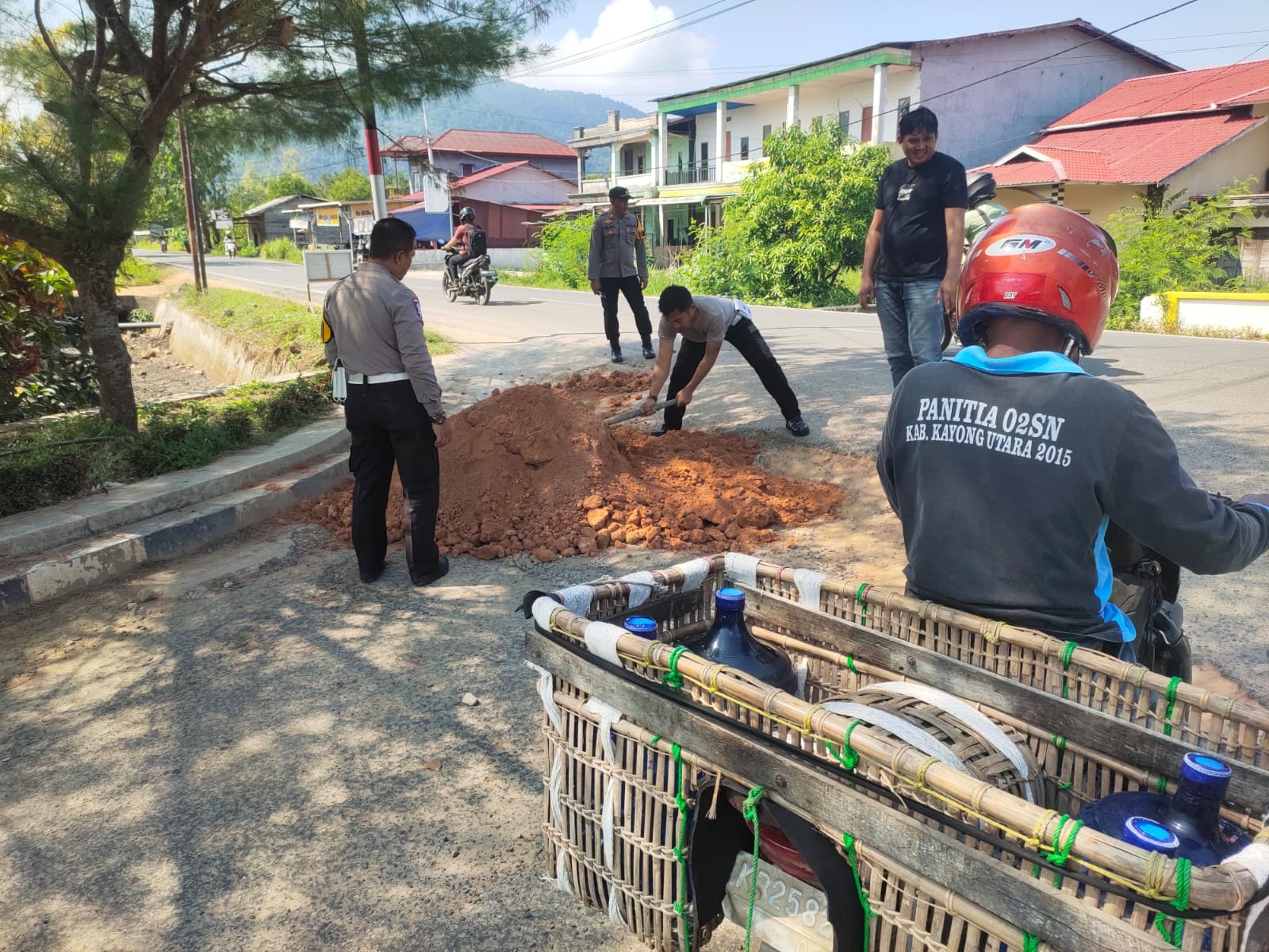 PEDULI JALAN RUSAK: Kasatlantas Polres Kayong Utara, IPTU Asep Engkim, bersama anggota dan warga, menimbun jalan berlubang di Simpang Empat Batu Daya, Kamis (24/7).