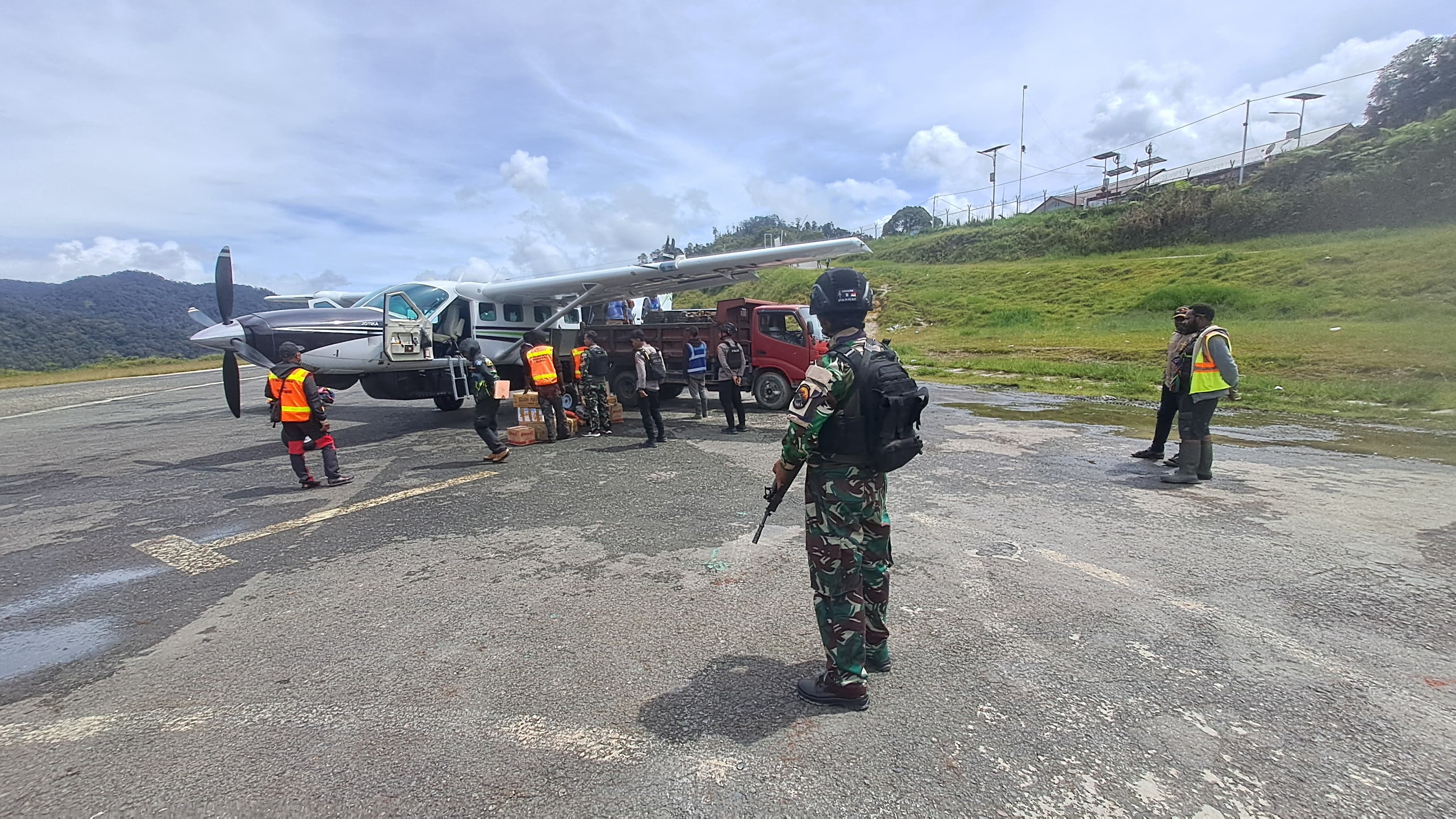 Satgas Kopasgat bersenjata amankan operasional Bandara Bilorai Sugapa, pesawat logistik bongkar muat di landasan.