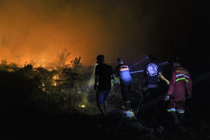 BERKOBAR: Petugas gabungan saat berusaha memadamkan kebakaran lahan gambut di kawasan Bandara Singkawang, Senin (28/7) malam.