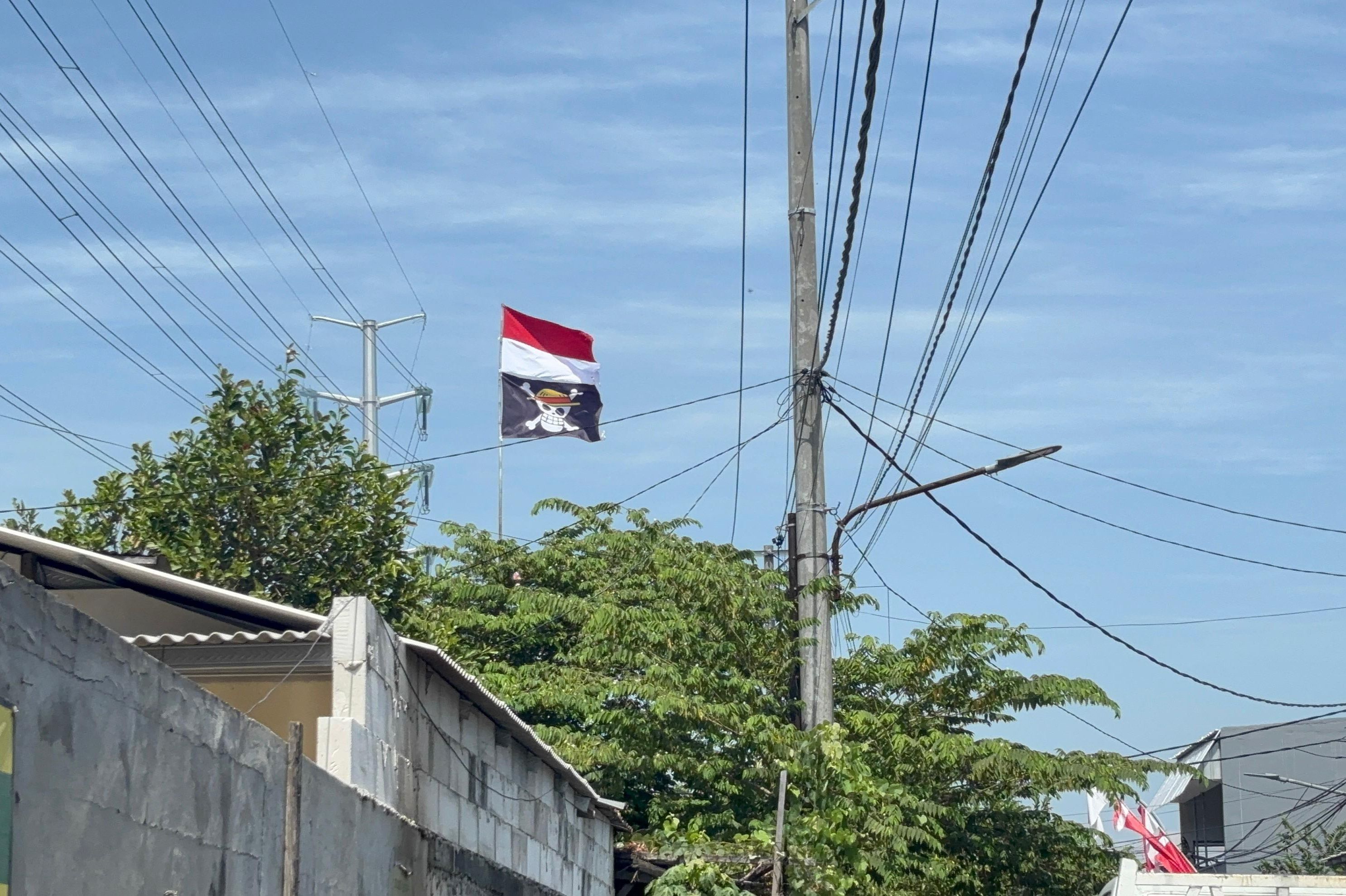 Bendera bajak laut One Piece dipasang warga di bawah bendera Merah Putih di Jalan Kejawan Putih Tambak, Mulyorejo, Surabaya.