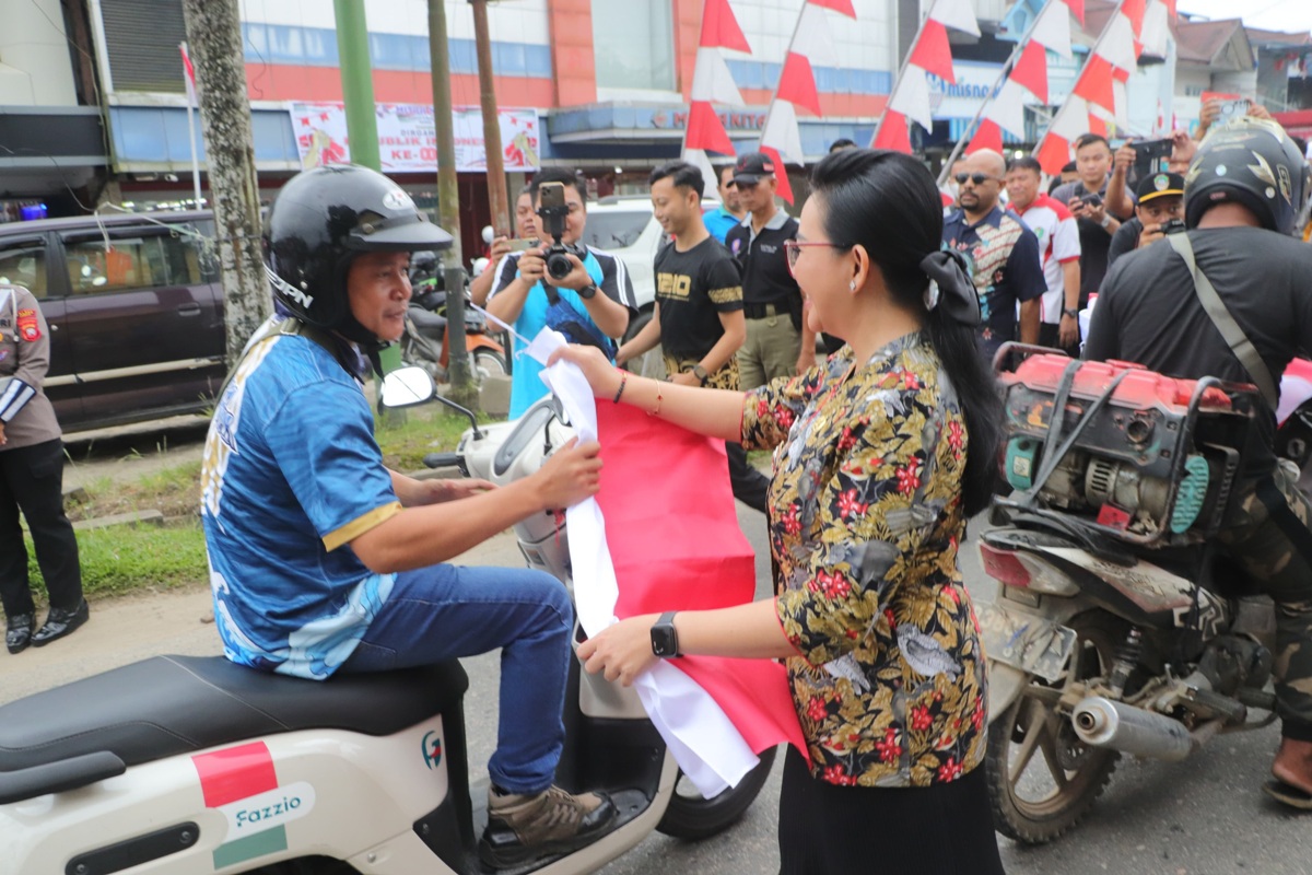 Bupati Landak Karolin Margret Natasa saat membagikan bendera merah putih untuk pengendara di Ngabang, Kabupaten Landak.