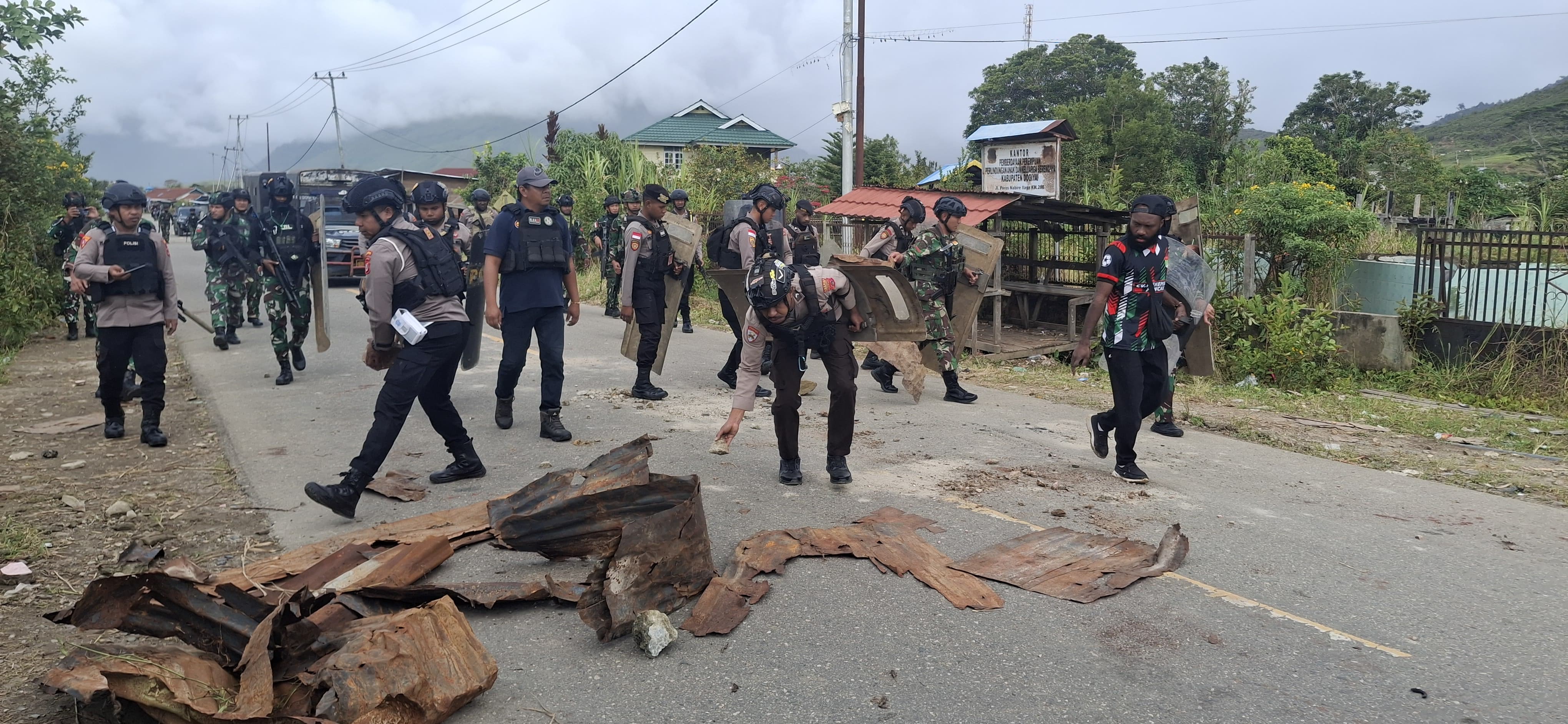 Personel TNI-Polri bersama warga membersihkan barikade dari jalan usai patroli keamanan di Moenamani, Dogiyai.