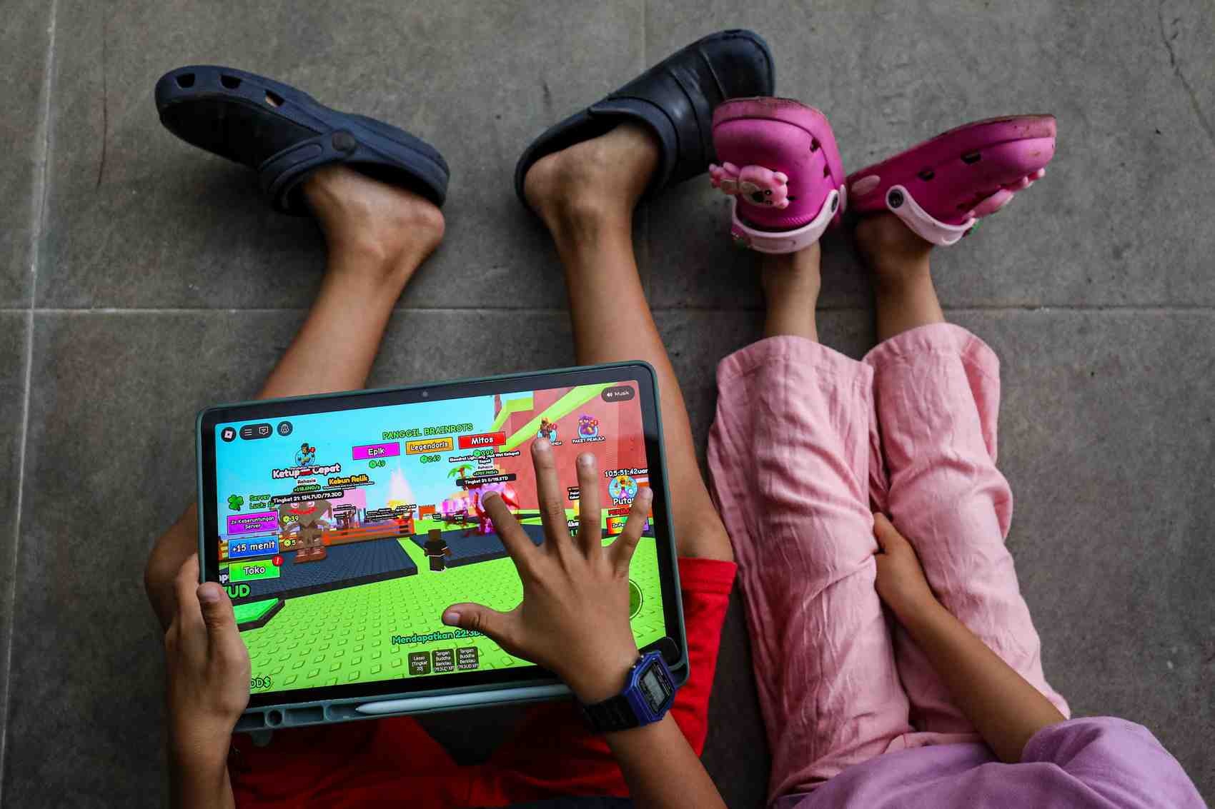 Anak-anak memainkan gim Roblox di sebuah tablet, di tengah wacana pemblokiran gim tersebut oleh pemerintah.