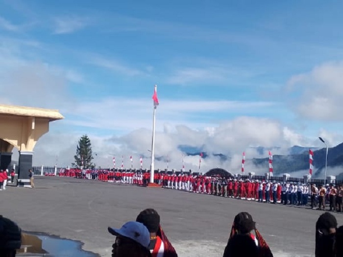Suasana khidmat upacara HUT ke-80 RI di Puncak Jaya, diwarnai barisan peserta berpakaian merah-putih dengan latar pegunungan.
