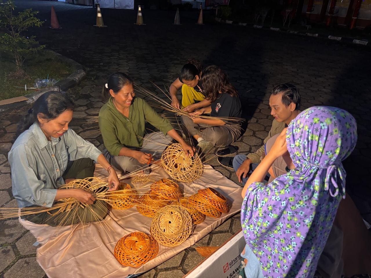Lusiana (kedua dari kiri) menganyam dan berinteraksi dengan pengunjung soal proses pembuatan kerajinan lidi sawit.