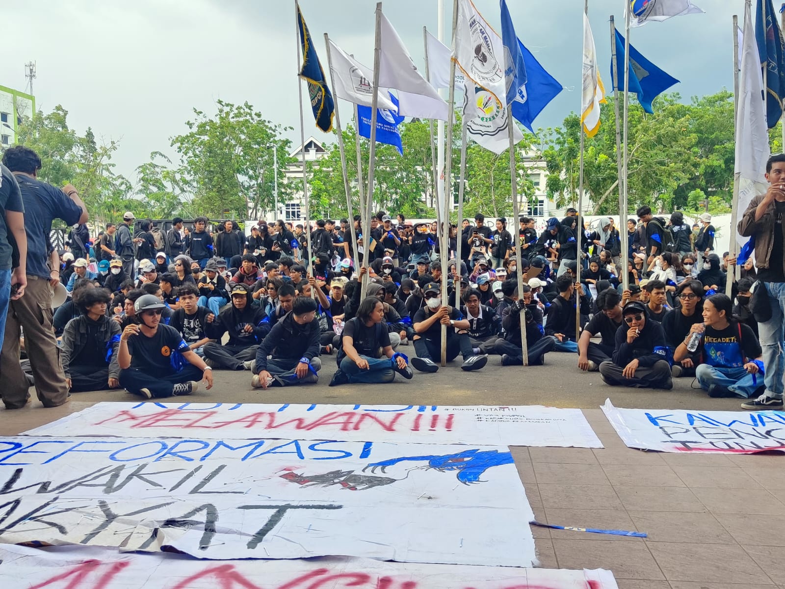 Mahasiswa berpita biru duduki halaman DPRD Kalbar, menuntut transparansi dana pensiun DPR dalam aksi damai.