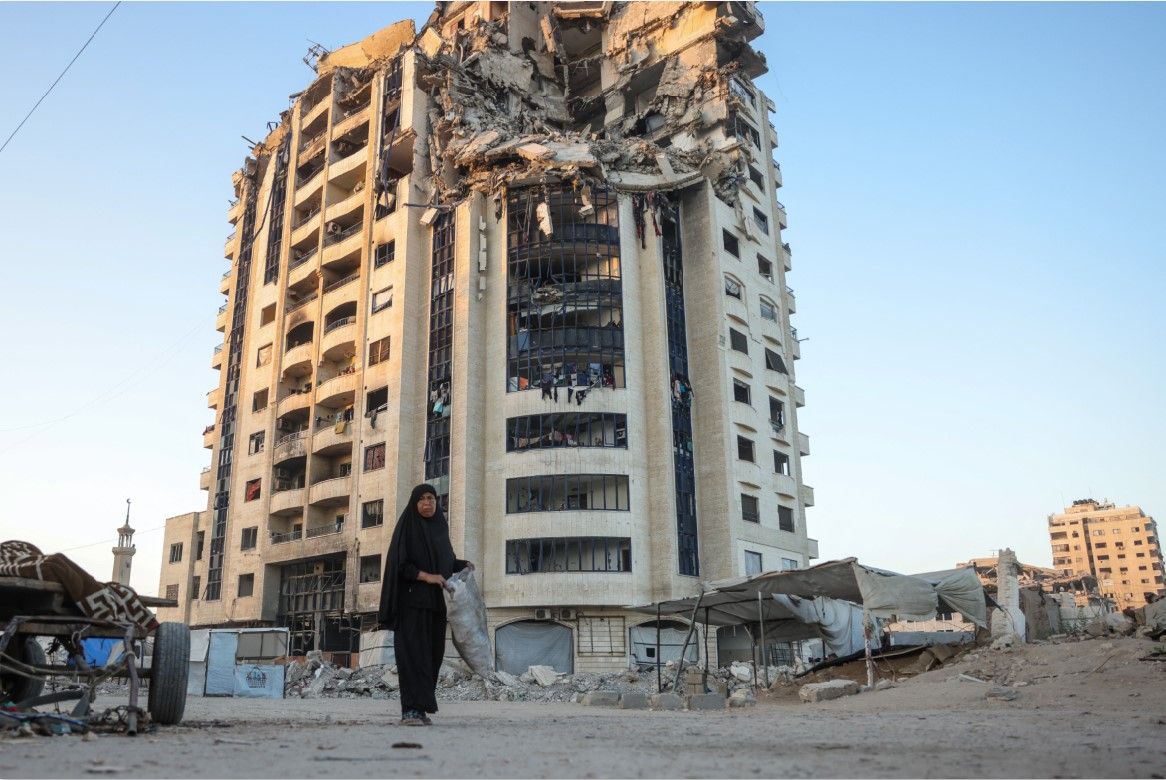 KIAN GENCAR: Seorang perempuan melintas di depan gedung yang hancur akibat serangan Israel di Gaza, Jumat (29/8). Israel kian gencar menyerang Gaza di tengah upaya gecatan senjata.